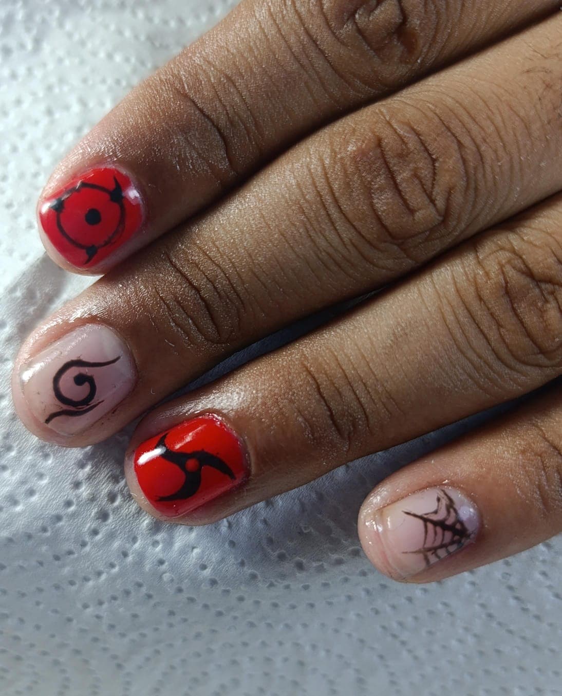 Uñas cortas rojas con diseños anime y telaraña
